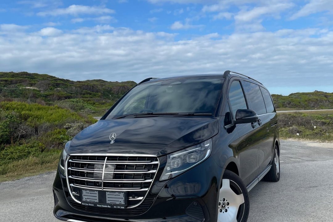 A black Mercedes-Benz V-Class from the Foreverlit fleet parked on a coastal road